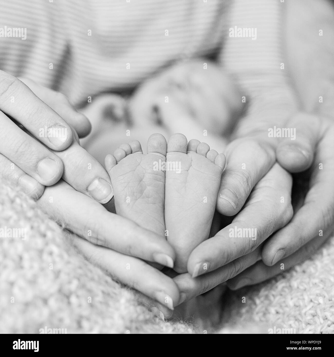 Piedi del neonato piedi nelle mani di padre, foto in bianco e nero. La nascita, la felicità e la famiglia felice concetto Foto Stock