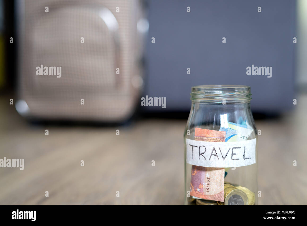 Il vasetto di vetro sul pavimento marcato in viaggio la messa a fuoco e una borsa da viaggio in background al di fuori della messa a fuoco. Pavimento in legno. Foto Stock