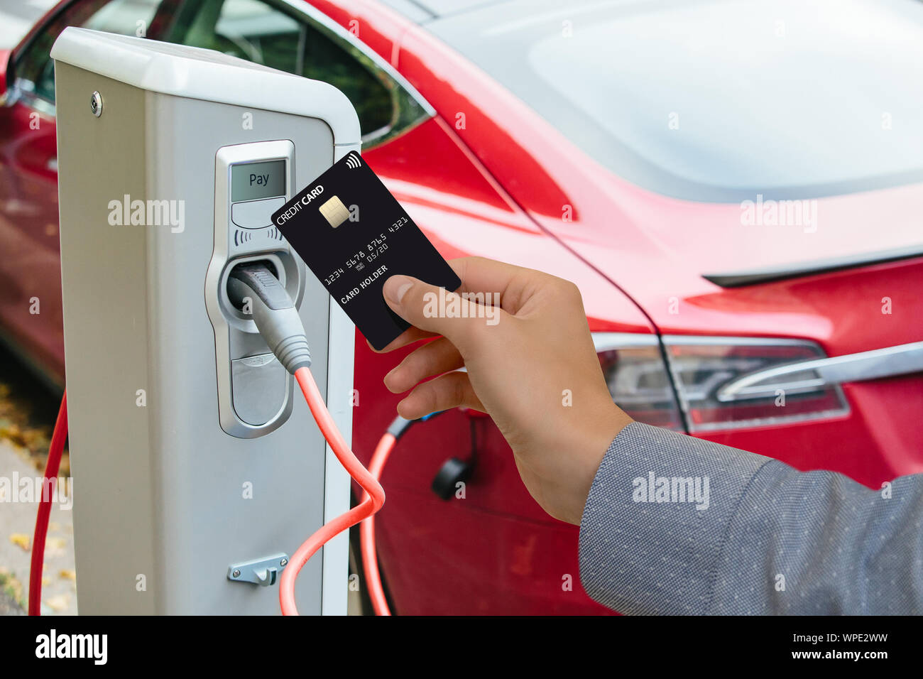 Un uomo paga per la ricarica di un auto elettrica. Foto Stock