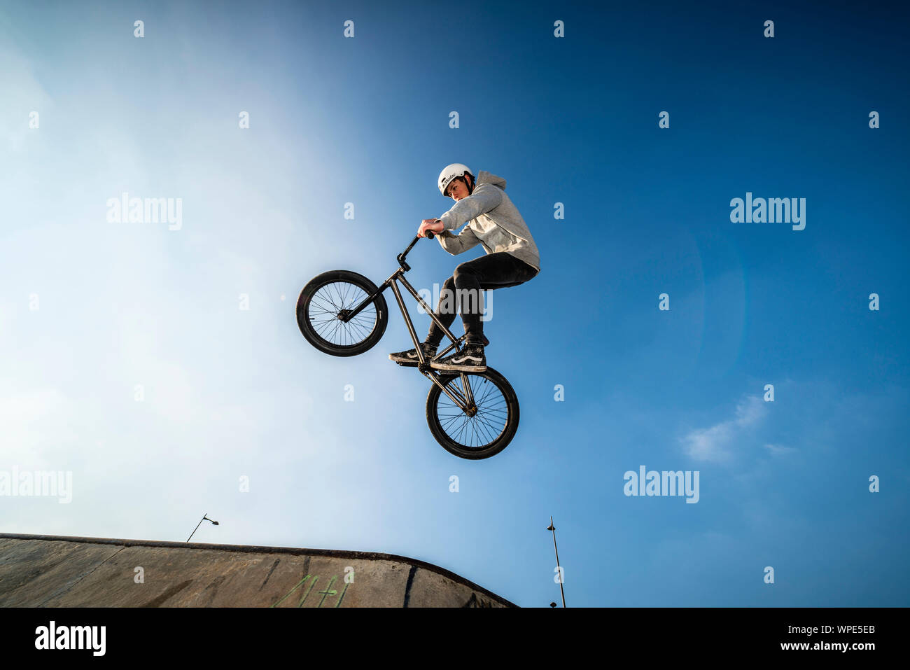 Adolescente di saltare in aria con la sua bici BMX in uno skate park. Foto Stock