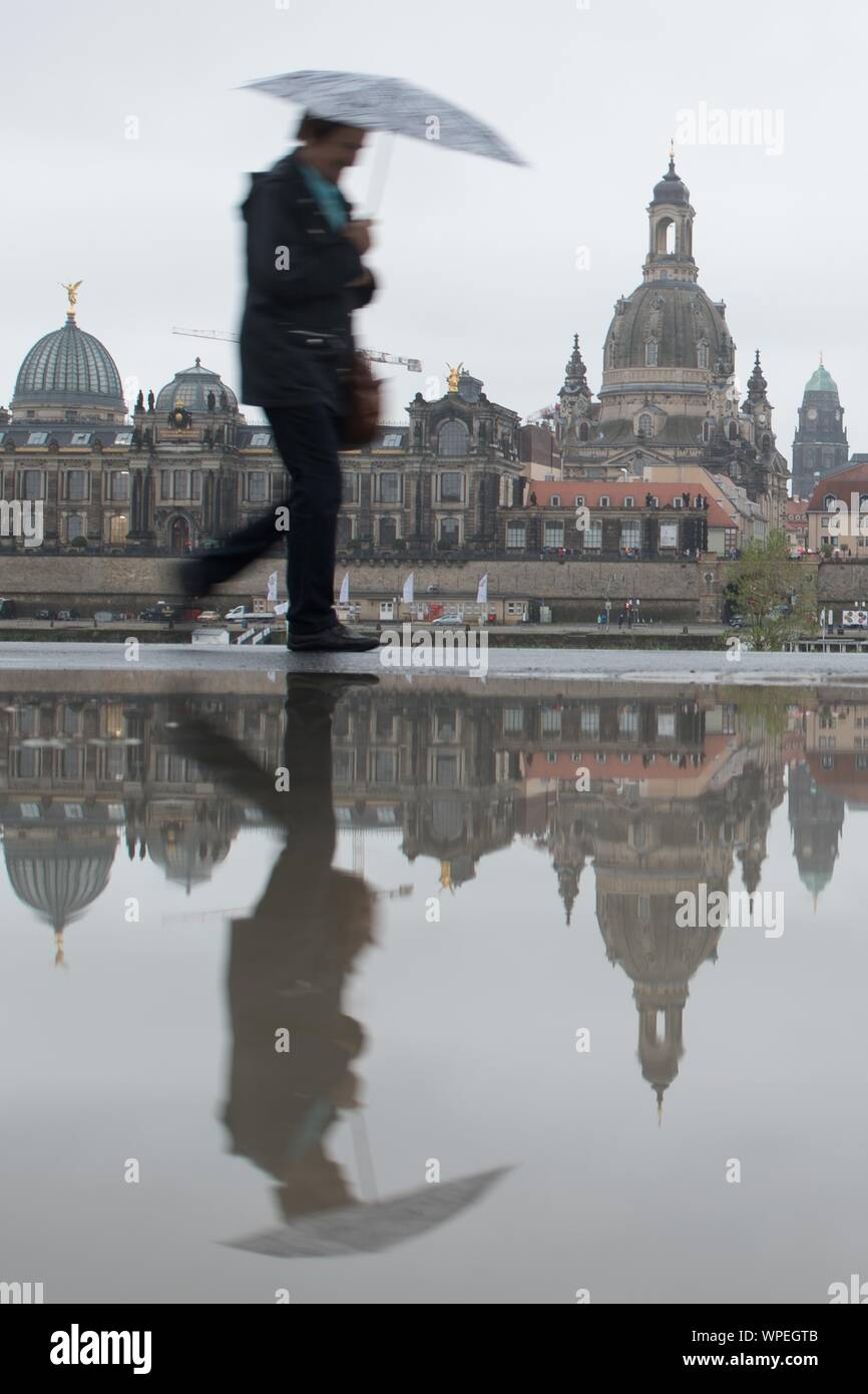 Dresden, Germania. 09Sep, 2019. Un passante da passeggiate lungo le rive del fiume Elba con un ombrello contro lo sfondo della città vecchia ed è riflessa in una pozzanghera. Credito: Sebastian Kahnert/dpa-Zentralbild/ZB/dpa/Alamy Live News Foto Stock