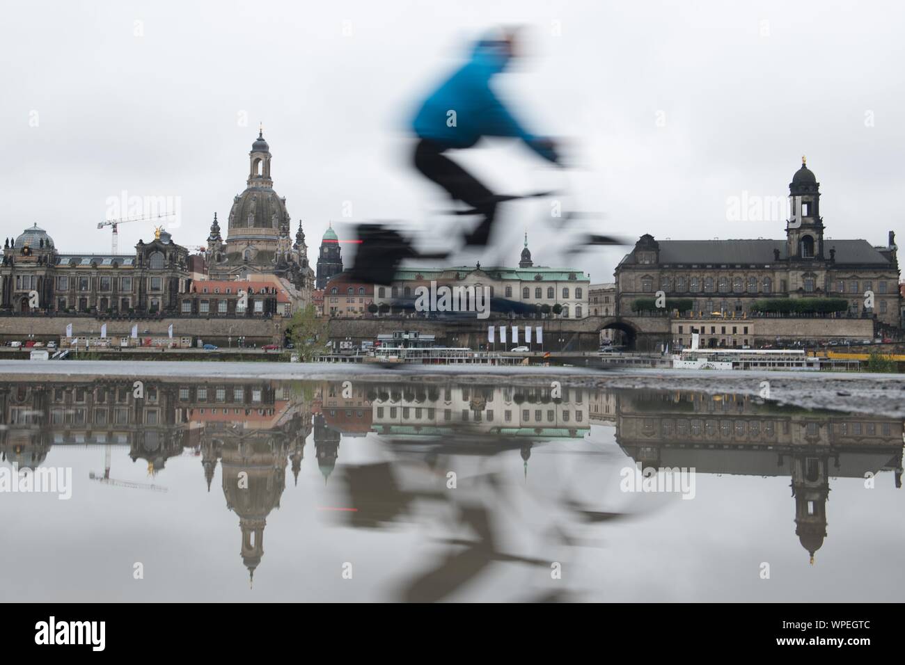 Dresden, Germania. 09Sep, 2019. Un ciclista viaggia lungo le rive del fiume Elba sullo sfondo della città vecchia su una pista ciclabile e si riflette in una pozzanghera. Credito: Sebastian Kahnert/dpa-Zentralbild/ZB/dpa/Alamy Live News Foto Stock