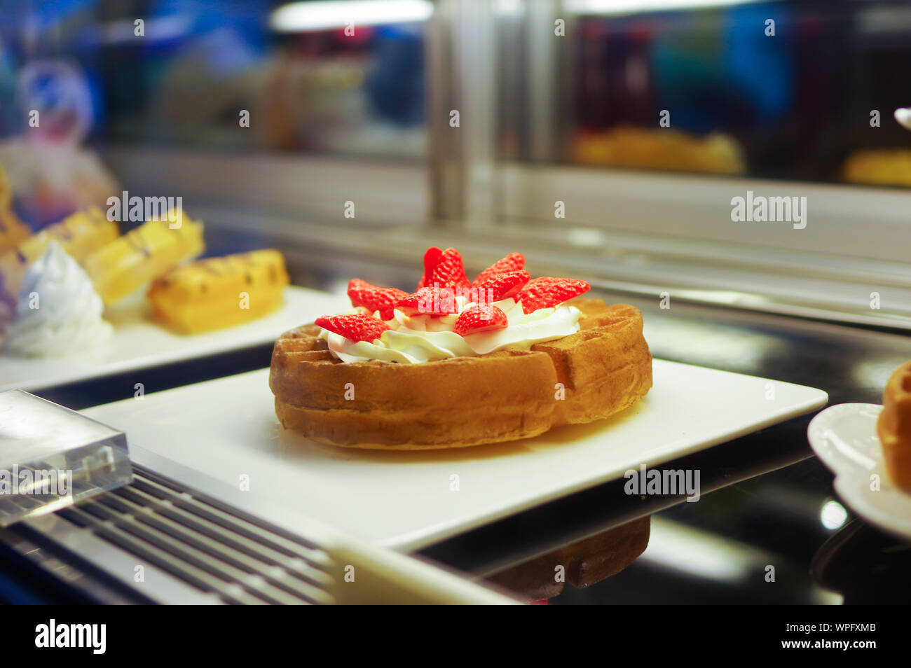 Fake fragola crema waffle puntelli modello visualizzato sulla piastra bianca in cafe frigorifero Foto Stock