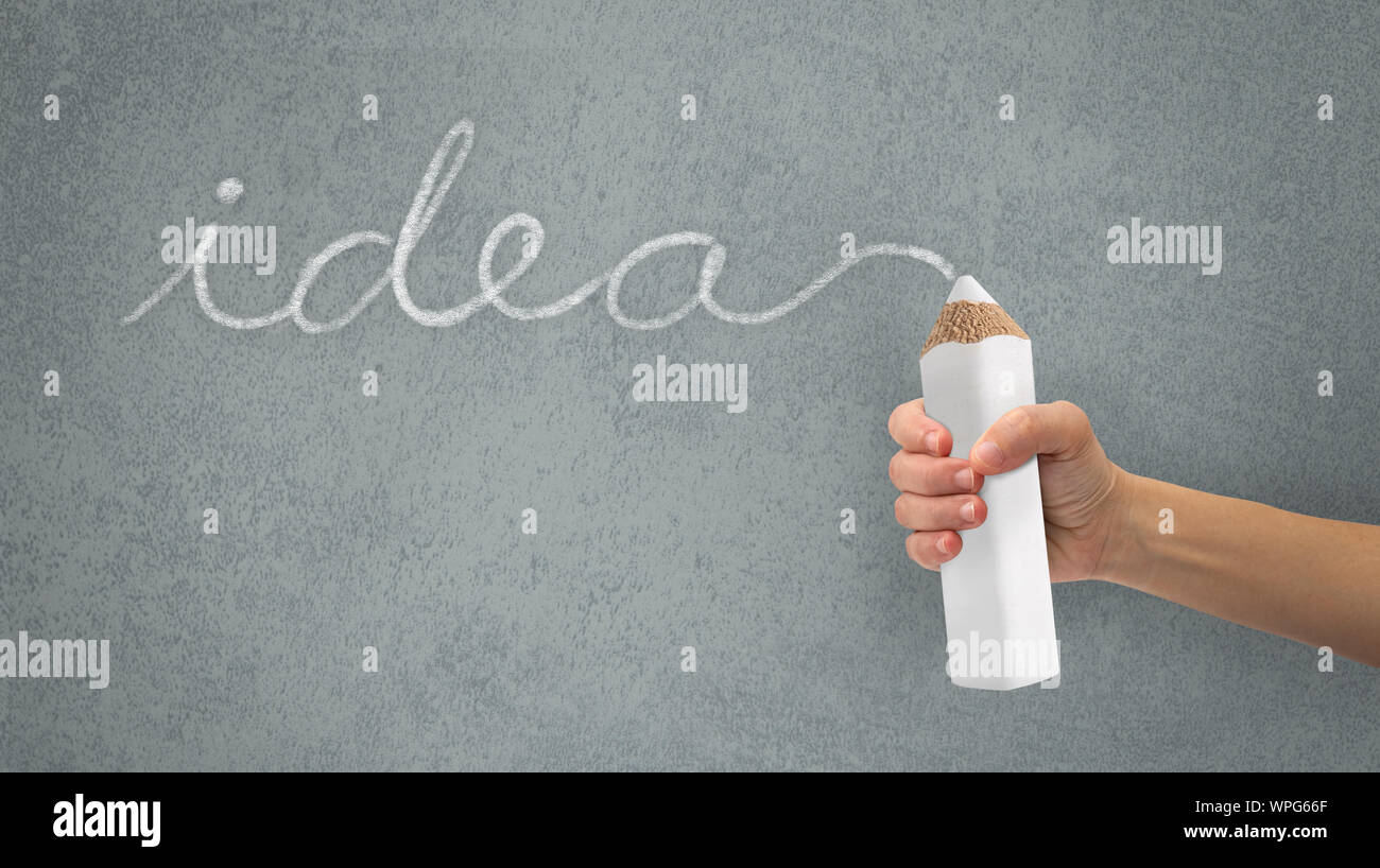 Mano che tiene una matita di grandi dimensioni. Scrivere la parola idea. Concetto di idee. Foto Stock