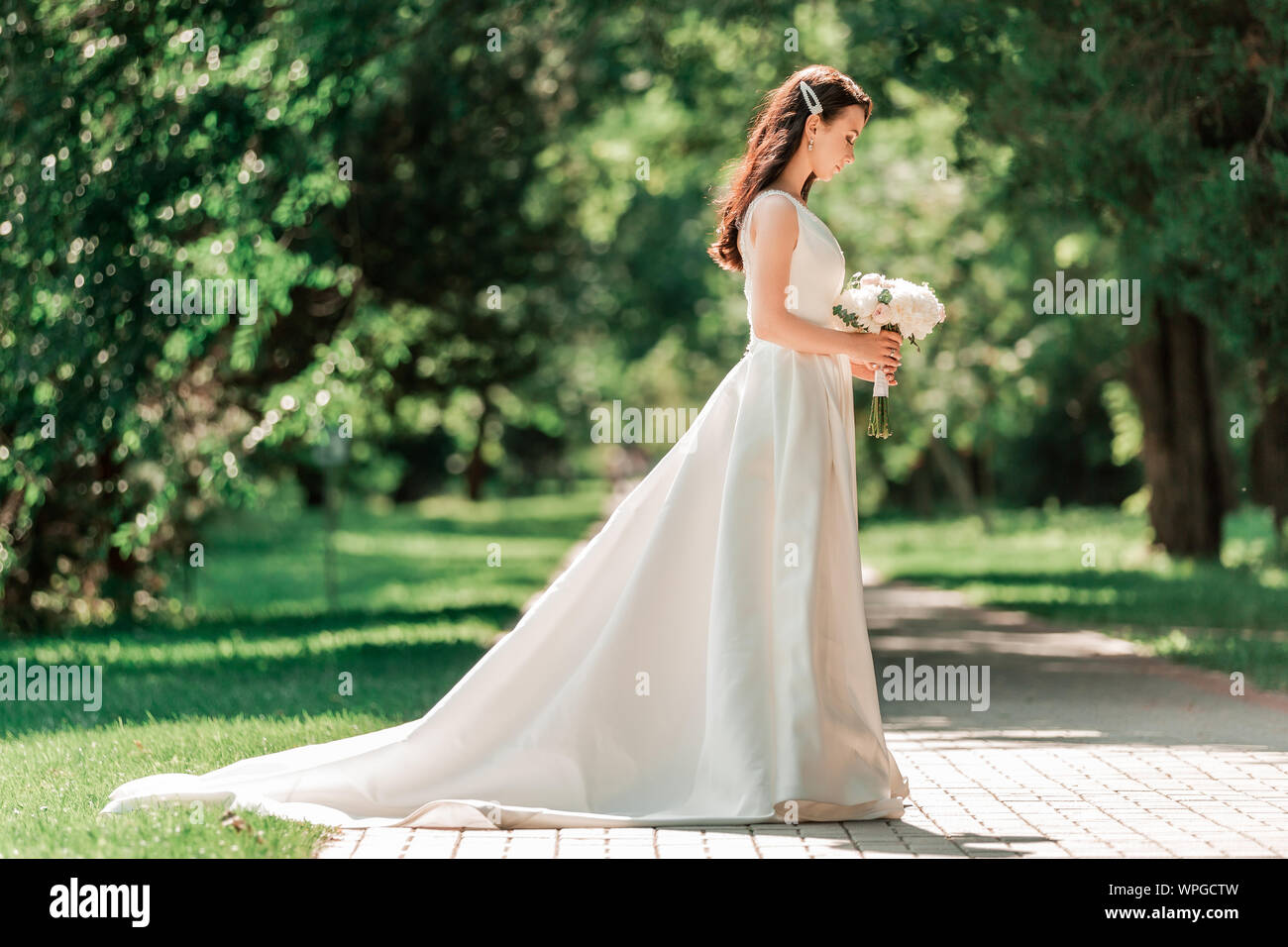 Bella giovane donna in abito da sposa in piedi nel parco. Foto Stock