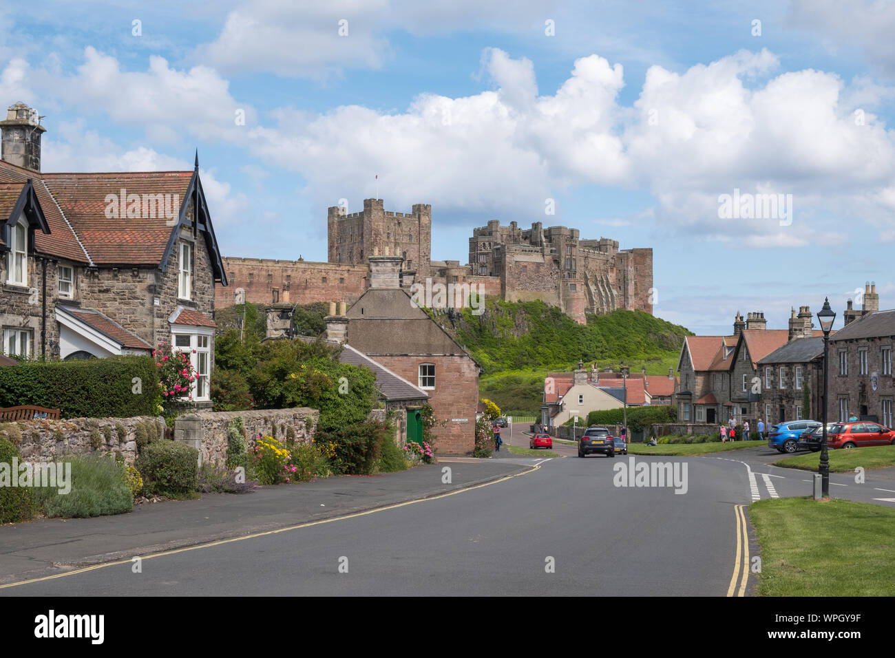 Front Street nel villaggio di Bamburgh sulla costa di Northumberland, Regno Unito con il castello di Bamburgh in background Foto Stock