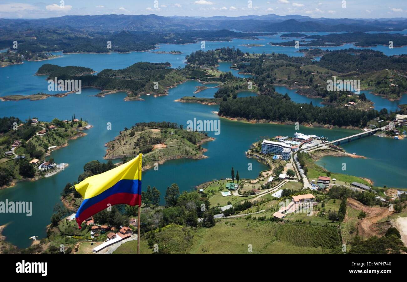 Bandiera colombiana agitando contro gli alberi e il fiume Foto Stock