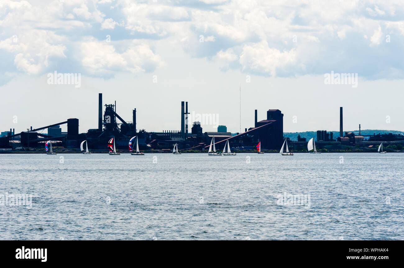 HAMILTON, ONTARIO, CANADA - Luglio 03, 2016: Barche a vela volare colorato spinnaker vele mentre passa dalla zona industriale di Hamilton Harbour. Foto Stock