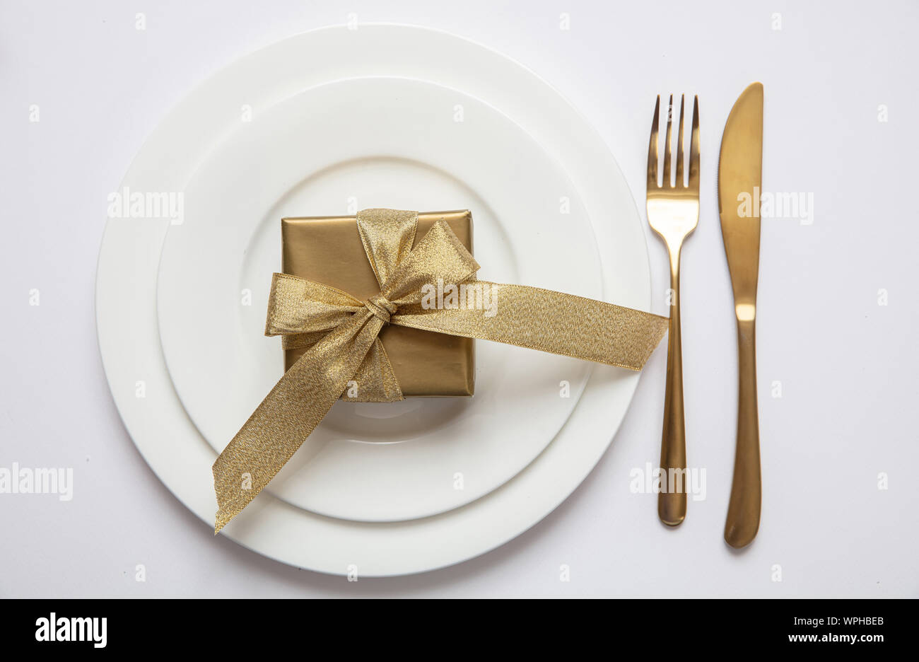 Cena di gala impostazione tabella, Gold confezione regalo e posate sul set di bianco di piatti isolati, sfondo bianco, vista dall'alto Foto Stock