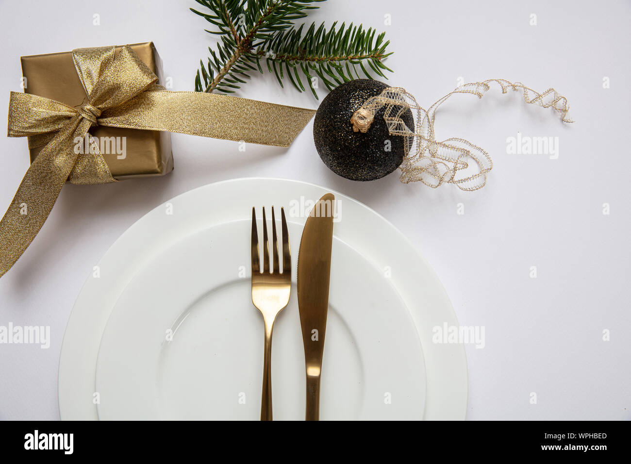 Cena Natale impostazione tabella, Gold confezione regalo e posate sul set di bianco di piatti, sfondo bianco, vista dall'alto Foto Stock