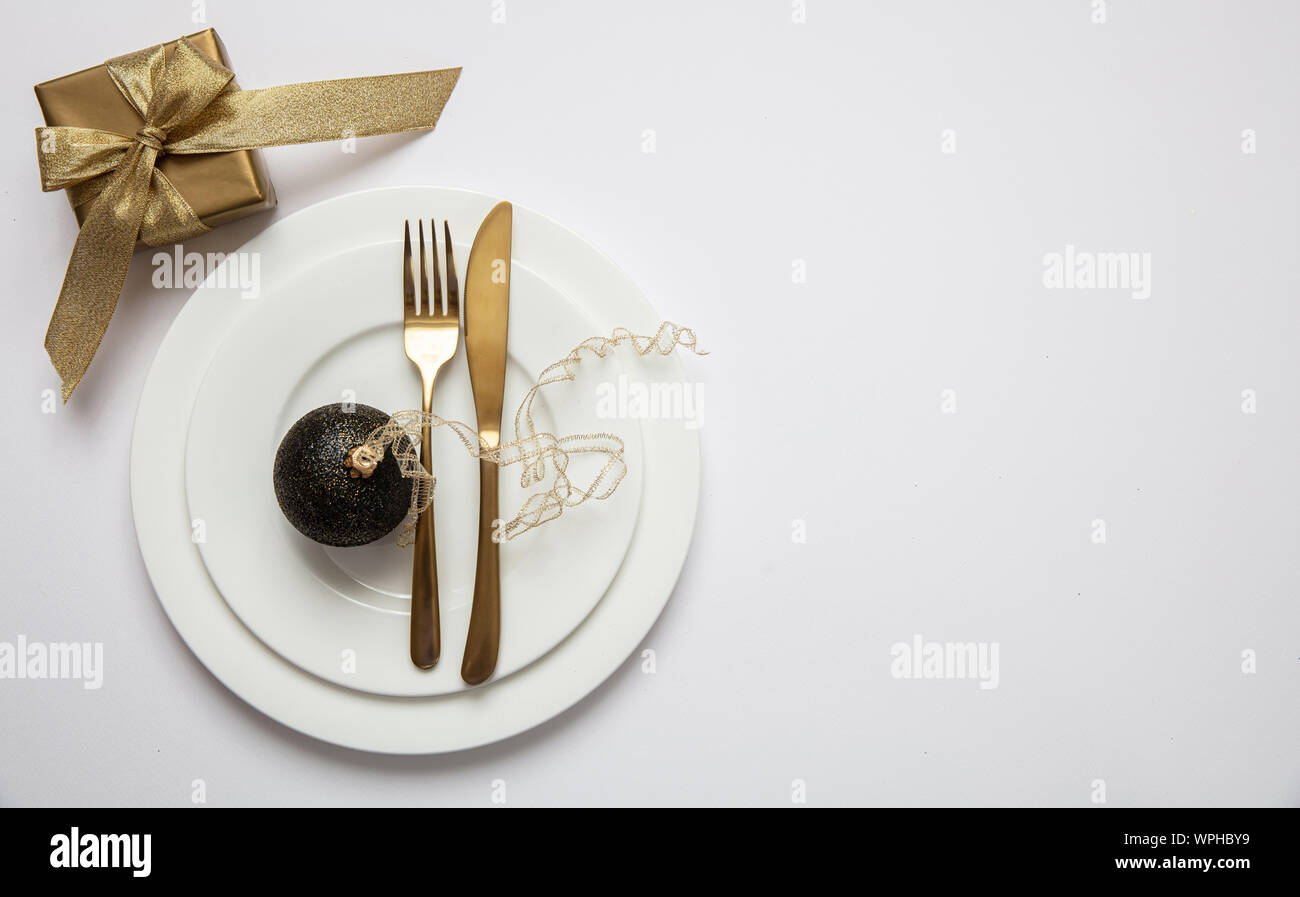 Cena Natale impostazione tabella, Gold confezione regalo e posate sul set di bianco di piatti, sfondo bianco, vista dall'alto, spazio di copia Foto Stock