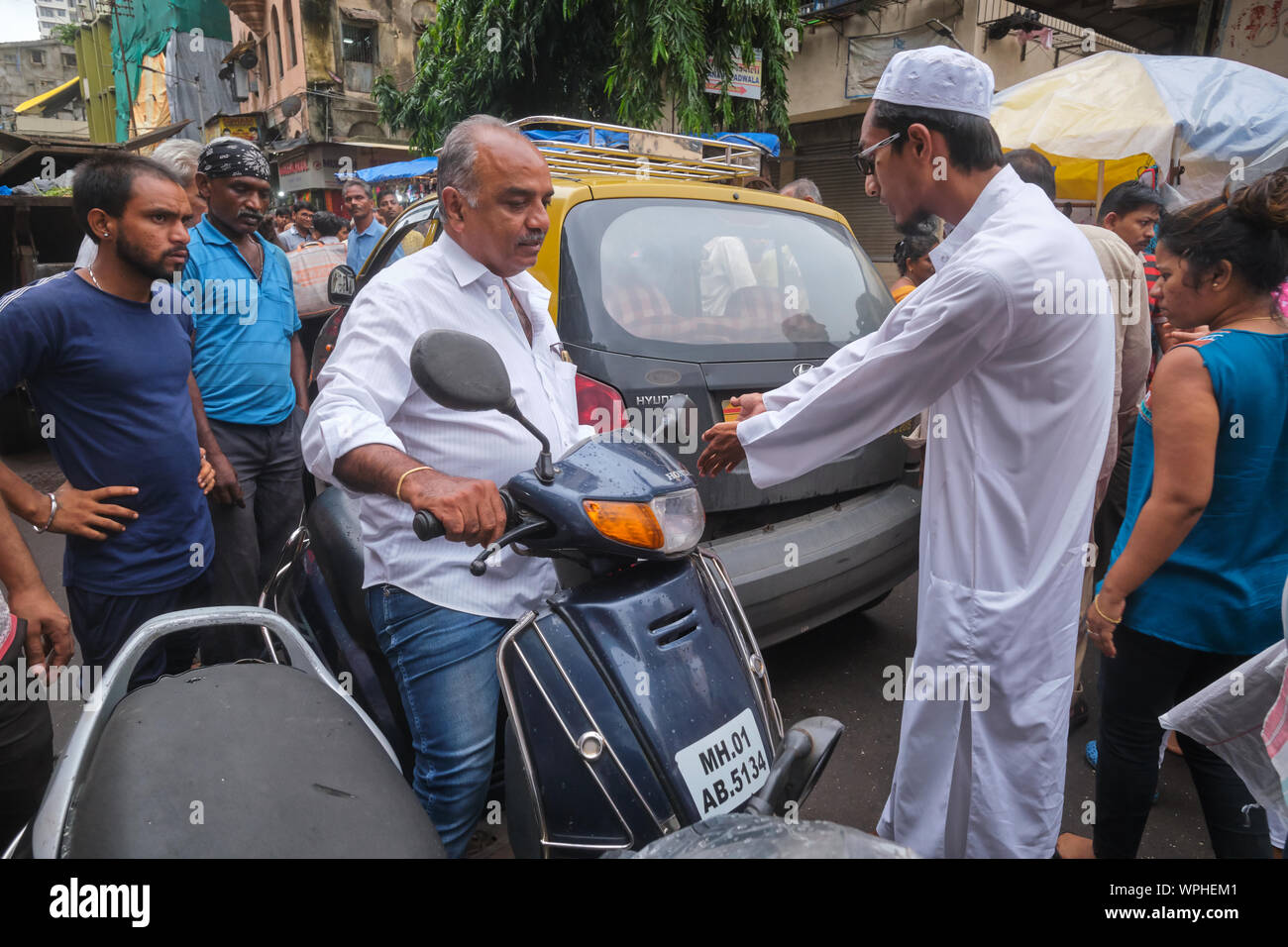 Guardate che cosa avete fatto al mio taxi: il traffico di una controversia in una corsia congestionato in Mumbai, India, tra un taxi driver (r) e un driver di scooter Foto Stock