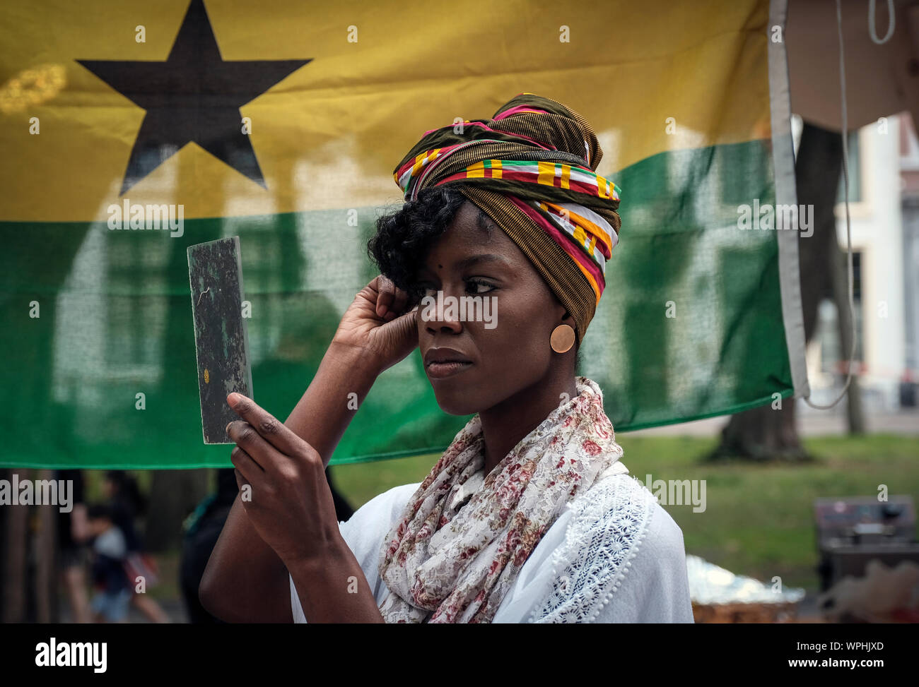 Uno dei partecipanti del Ghana stand mette sul suo tipico copricapo Foto Stock
