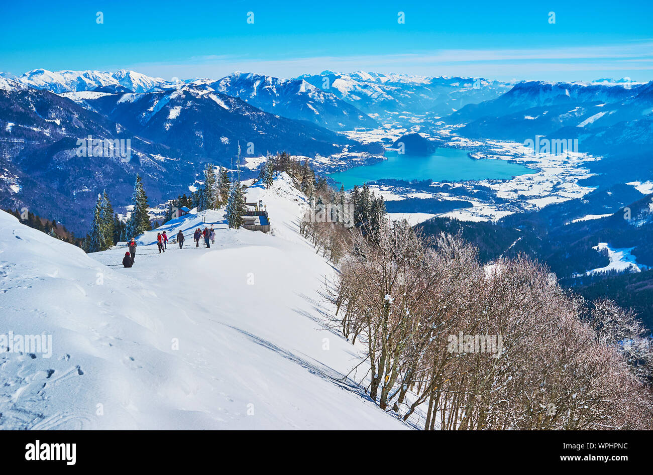 Gli sportivi e i turisti vanno in salita alla cima del monte Zwolferhorn per osservare il paesaggio alpino e godetevi il panorama invernale del Salzkammergut con Wolfg Foto Stock