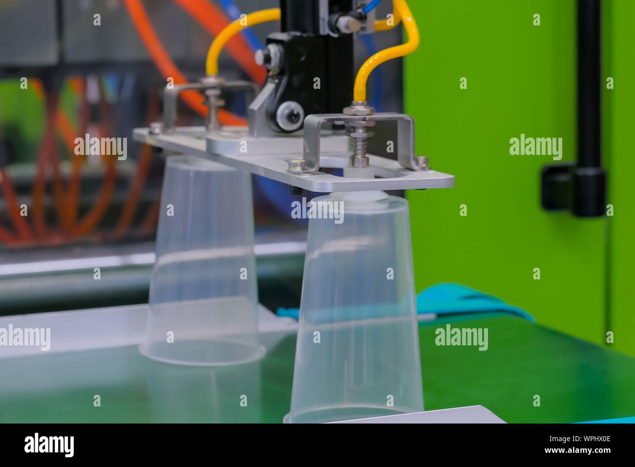 Tazze sul nastro trasportatore della macchina per lo stampaggio di materiale plastico con il braccio robotico Foto Stock