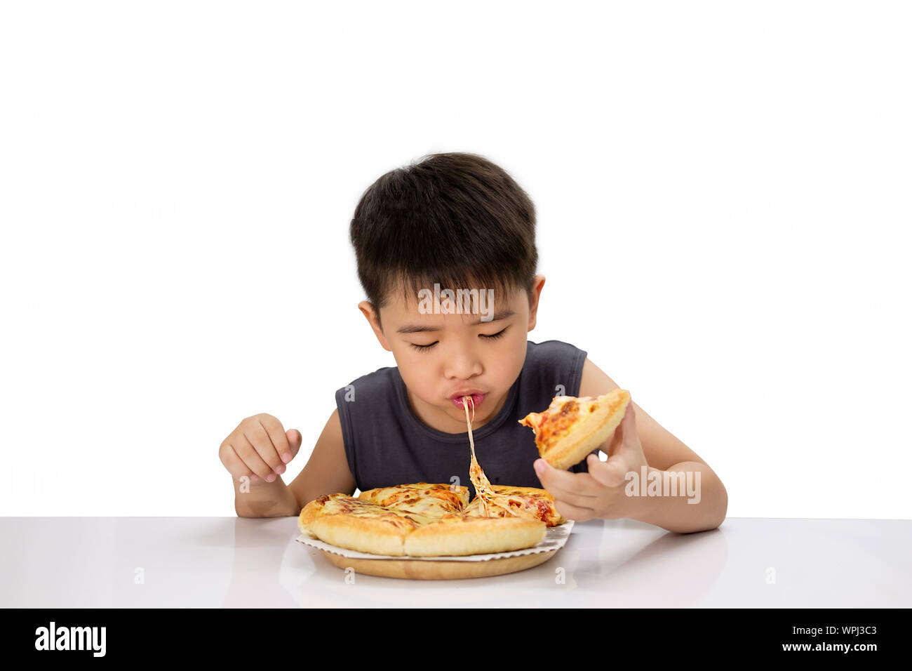 Ragazzo asiatico è felice di mangiare la pizza con un formaggio hot melt tesa su un tampone di legno. Isolato su bianco. Foto Stock