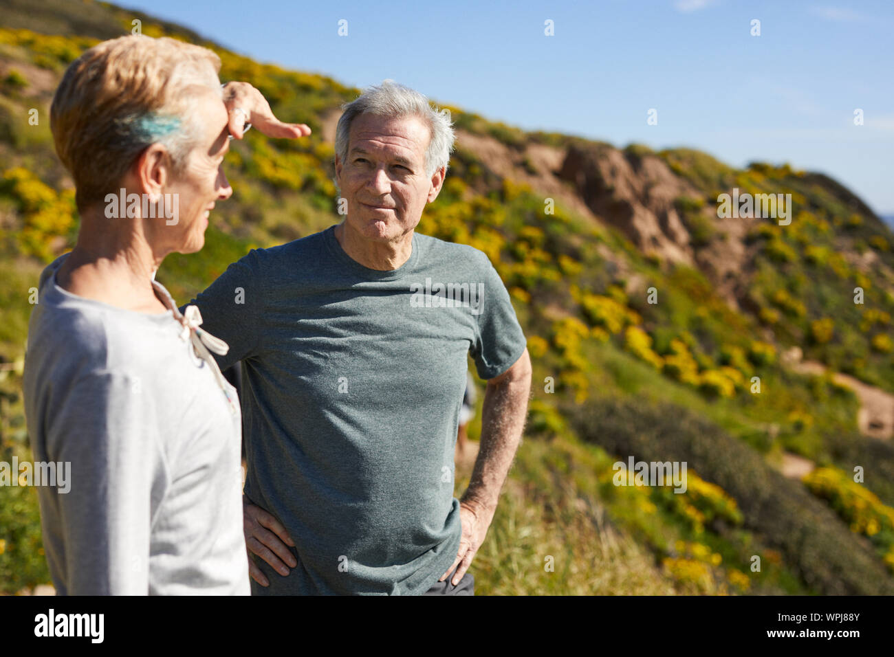 Attivo coppia senior permanente sulla scogliera durante la giornata di sole Foto Stock