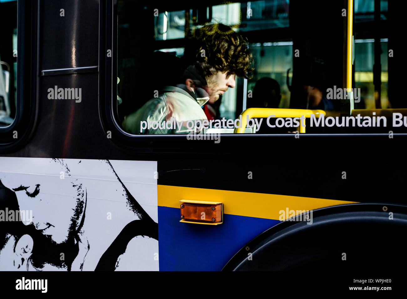 Street photography di uno straniero che è seduto in un autobus nella città di Vancouver in Canada. La luce del sole espone il suo volto drasticamente, ma egli rimane sconosciuto. Foto Stock