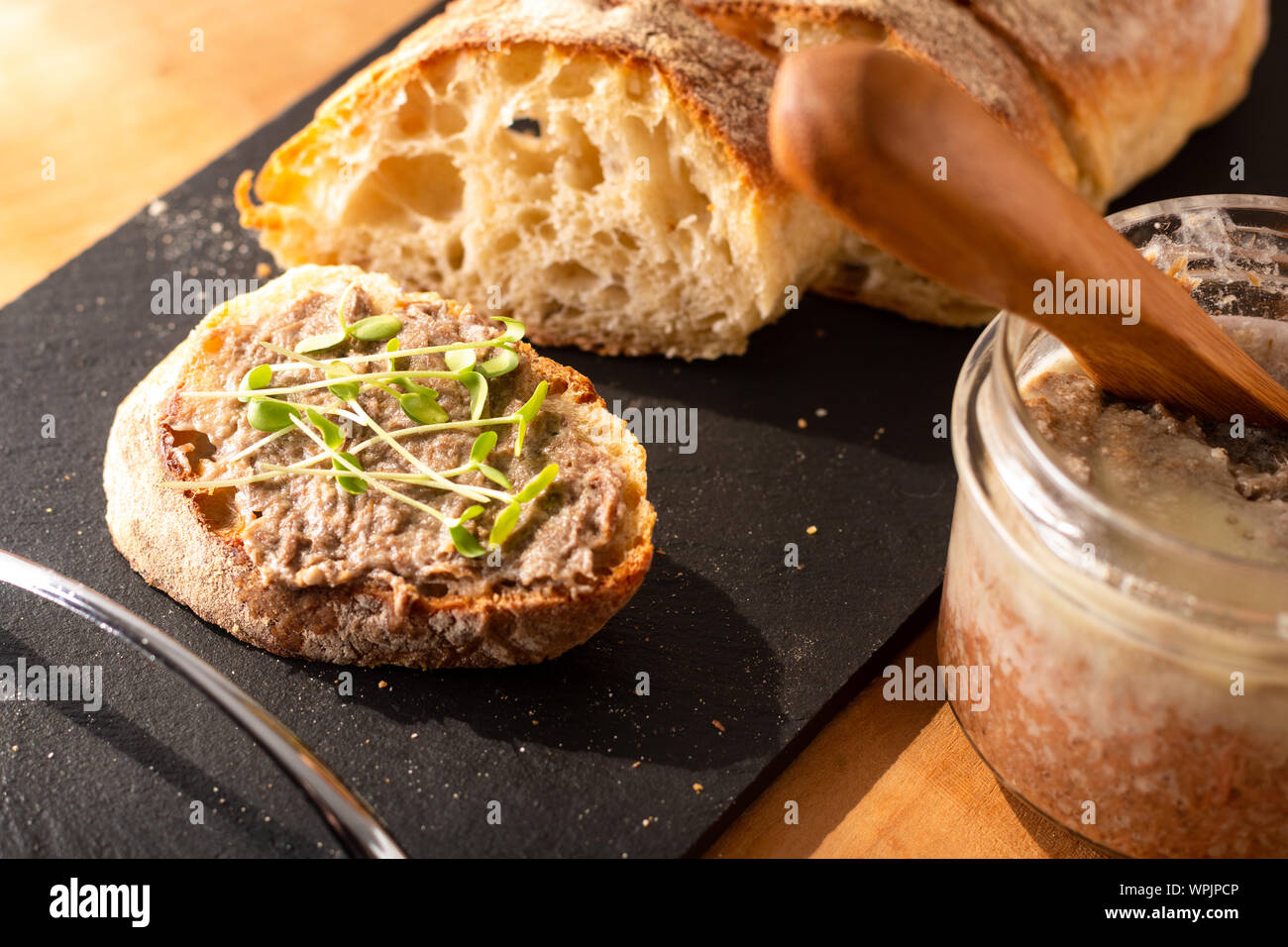 Concetto di cibo francese Rillettes potenzia la diffusione su fatti in casa artigiani croccante pane ciabatta con lino microgreen per la prima colazione o per uno spuntino di rottura Foto Stock