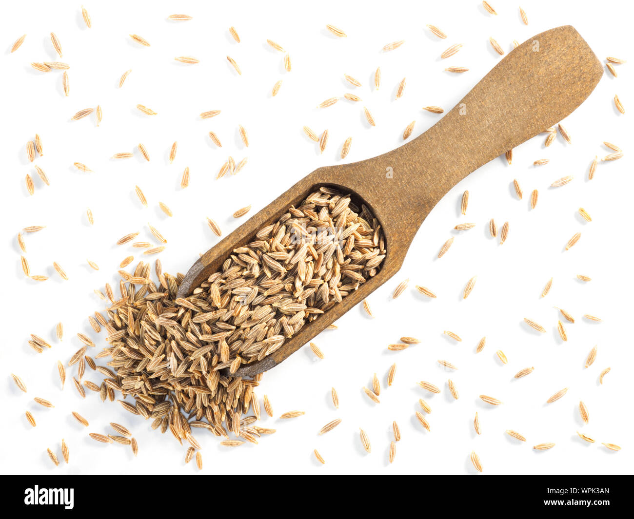 Semi di cumino (Cuminum), Jeera nel convogliatore di legno su uno sfondo bianco in diagonale Foto Stock