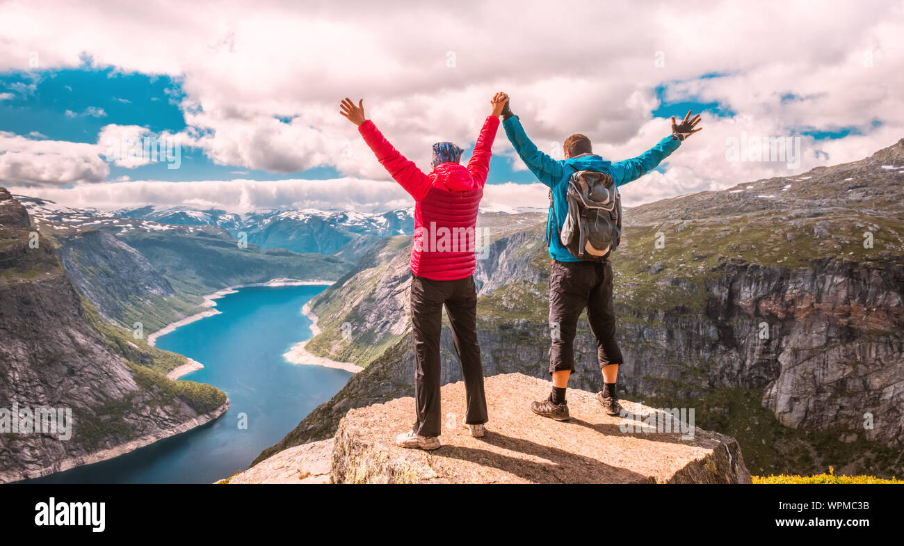 Matura in posa sul Trolltunga. Felice l'uomo e la donna godere del bellissimo lago e buone condizioni meteorologiche in Norvegia. Foto Stock