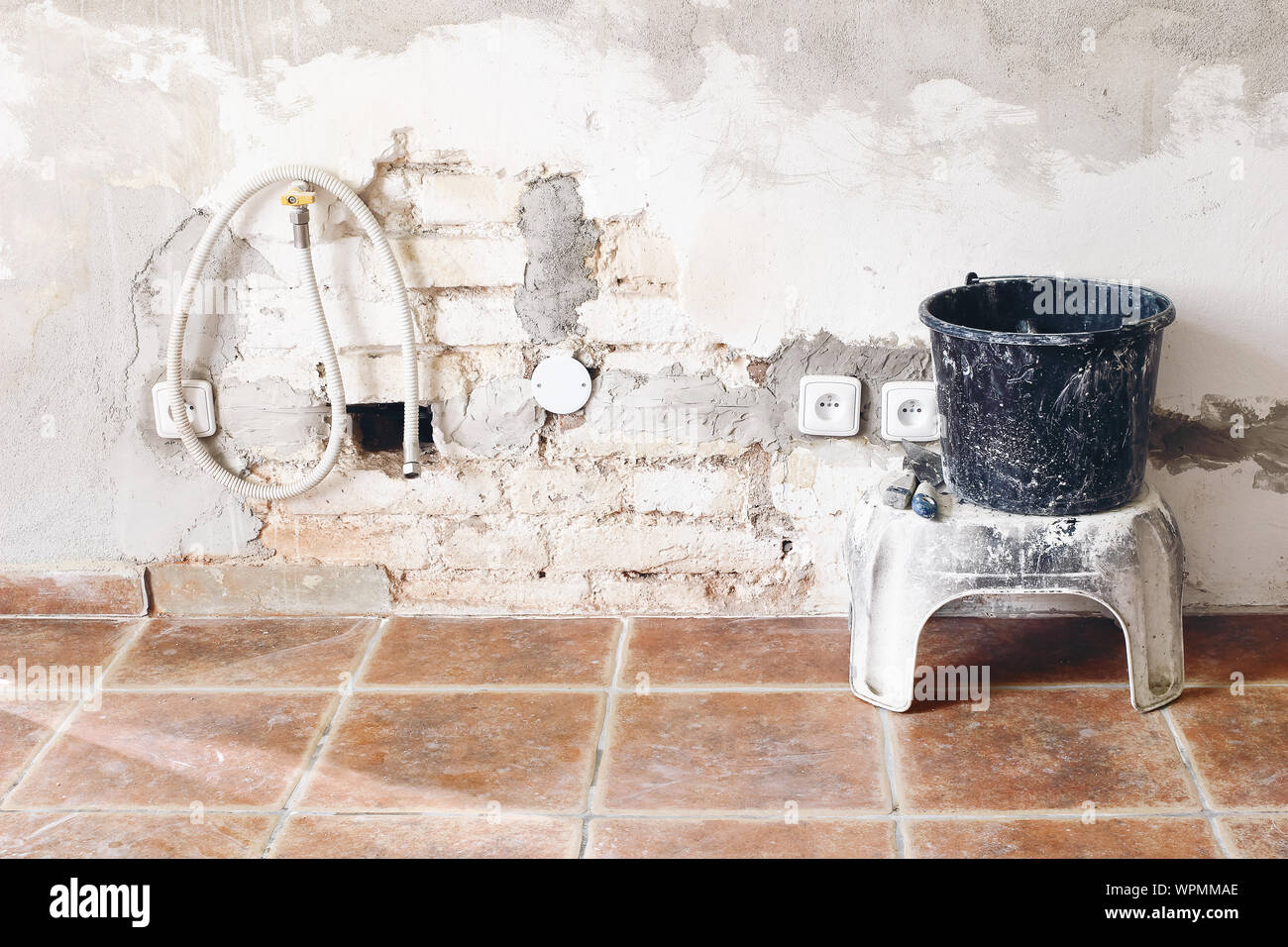 Nero benna sporca e la spatola strumenti bianco e un muro di mattoni. Camera incompiuta ricostruzione. Riparazione della casa, il miglioramento. Lavori in corso. La ricostruzione, ren Foto Stock