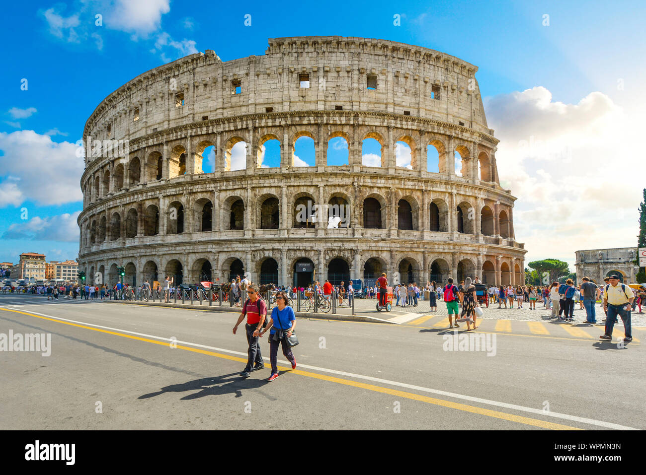 L'antica arena, il Colosseo di Roma in Italia in un giorno di estate con i turisti a piedi attraverso la Via dei Fori Imperiali Foto Stock