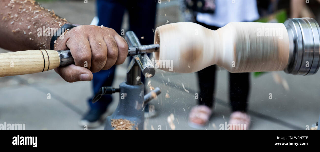 Un artigiano si ritaglia un pezzo di legno con un tornio. Foto Stock