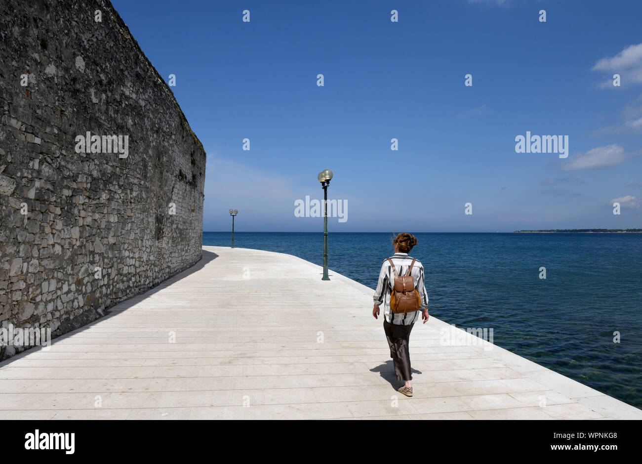 Donna che cammina sul lungomare a Porec, in Croazia Foto Stock