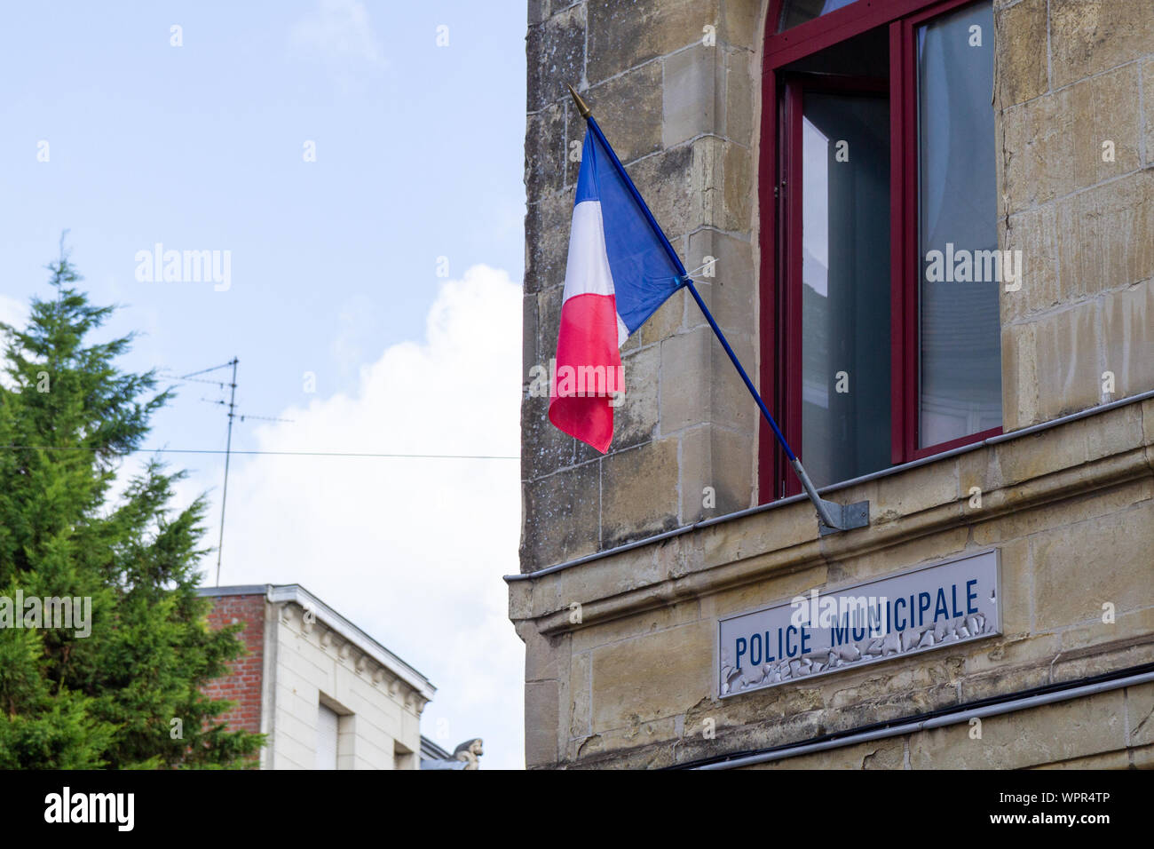 Una bandiera francese appeso sulla finestra della polizia municipale stazione di Valenciennes, Francia. Girato nel 2019. Foto Stock