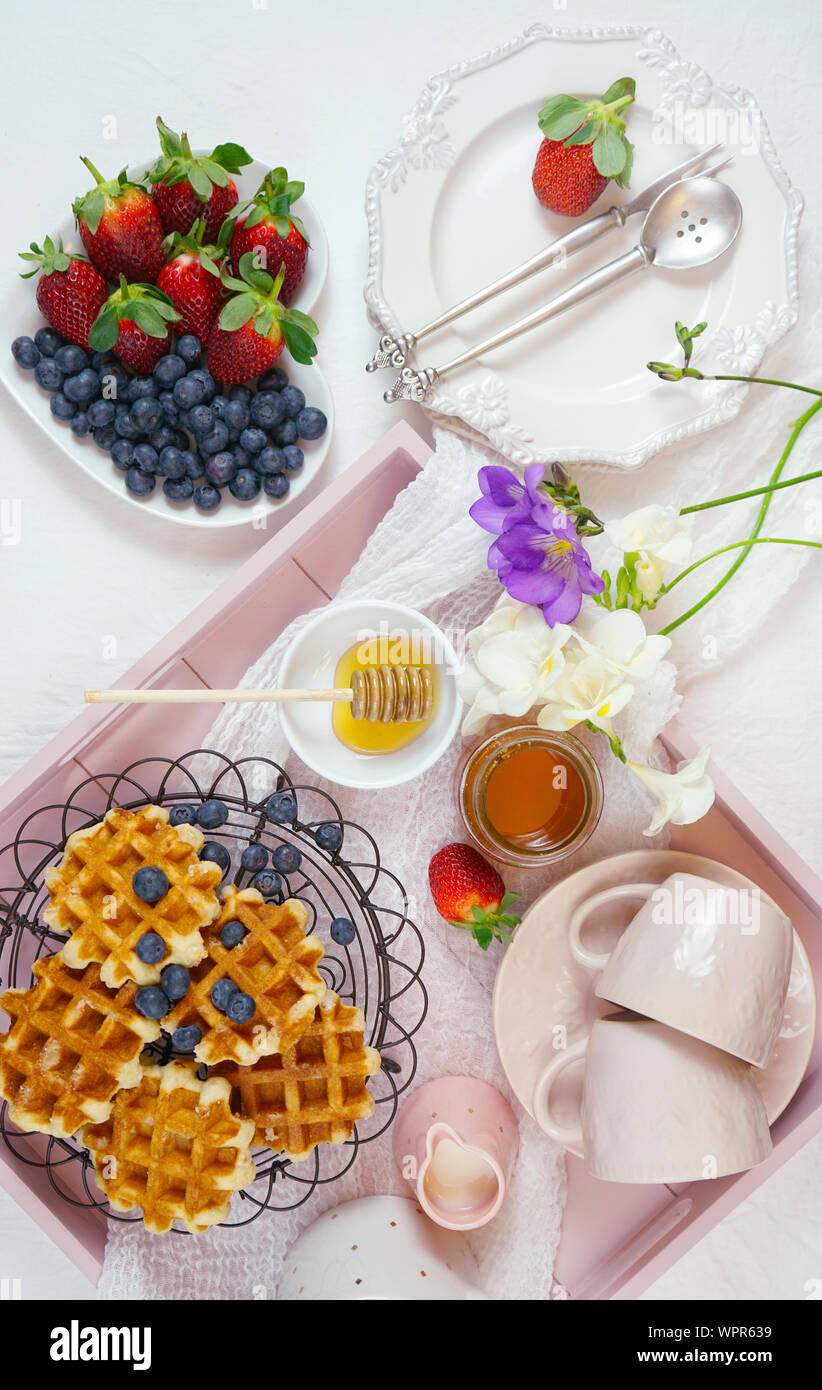 Moderno blush rosa vassoio colazione con cialde, miele e frutta. Foto Stock