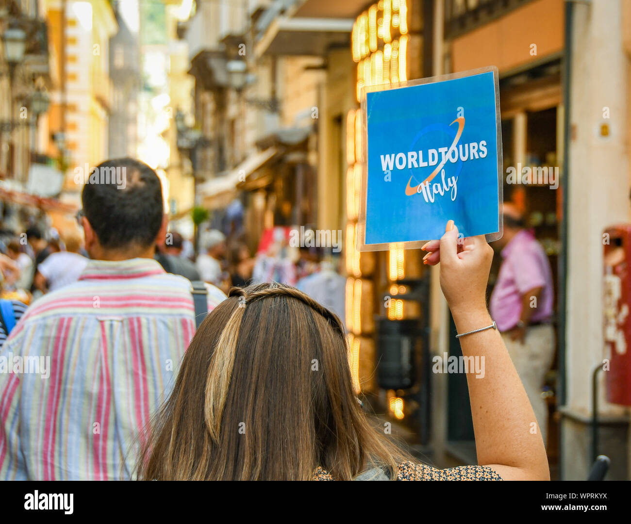 SORRENTO, ITALIA - Agosto 2019: Tour guida tenendo in mano un cartello per il suo gruppo di tour come essi a piedi attraverso il centro storico di Sorrento. Foto Stock