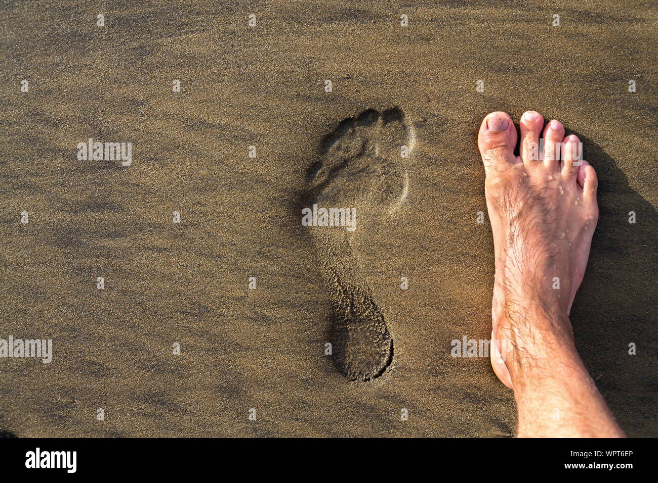 Footprint umana con piedi scalzi in marrone giallo sabbia spiaggia sfondo, active vivere sano e crescita personale concetto di spazio di copia Foto Stock