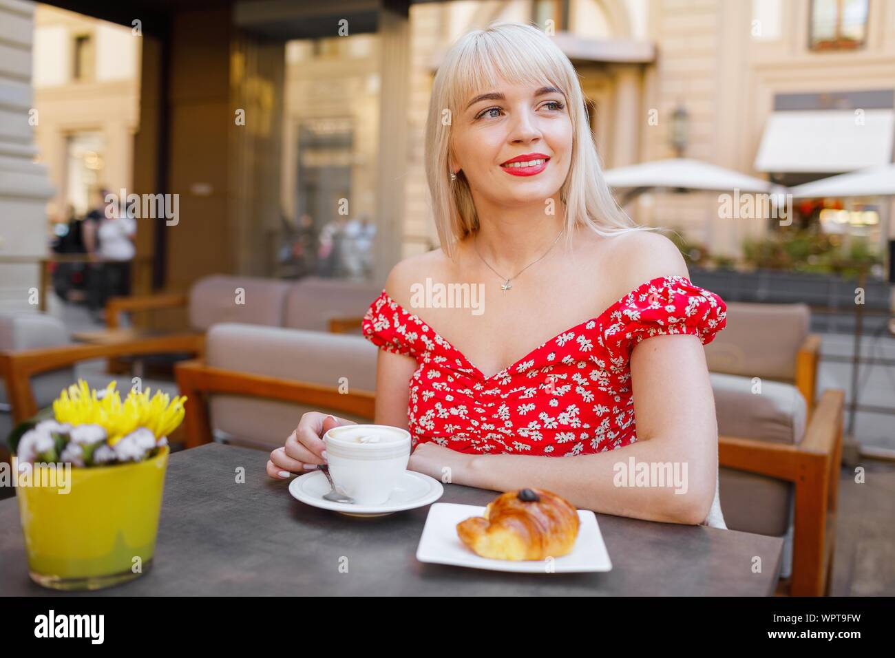 Giovane donna con prima colazione italiana con croissant e caffè un Foto Stock