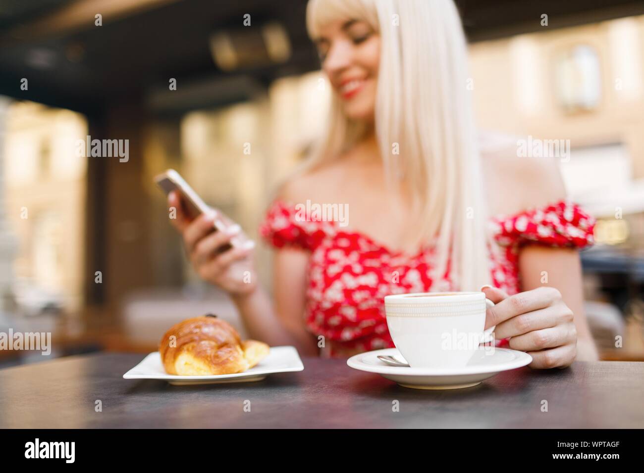 Giovane donna con prima colazione italiana con croissant e caffè un Foto Stock