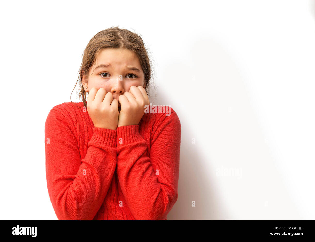 Ritratto di paura ragazza in piedi contro uno sfondo bianco Foto Stock
