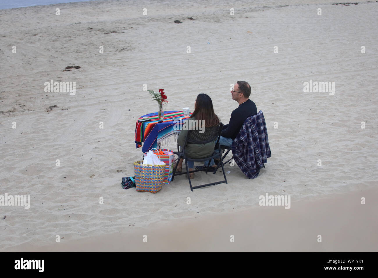 Un giovane condivide una parentesi romantica sulla spiaggia completo con fiori e un dono. Foto Stock