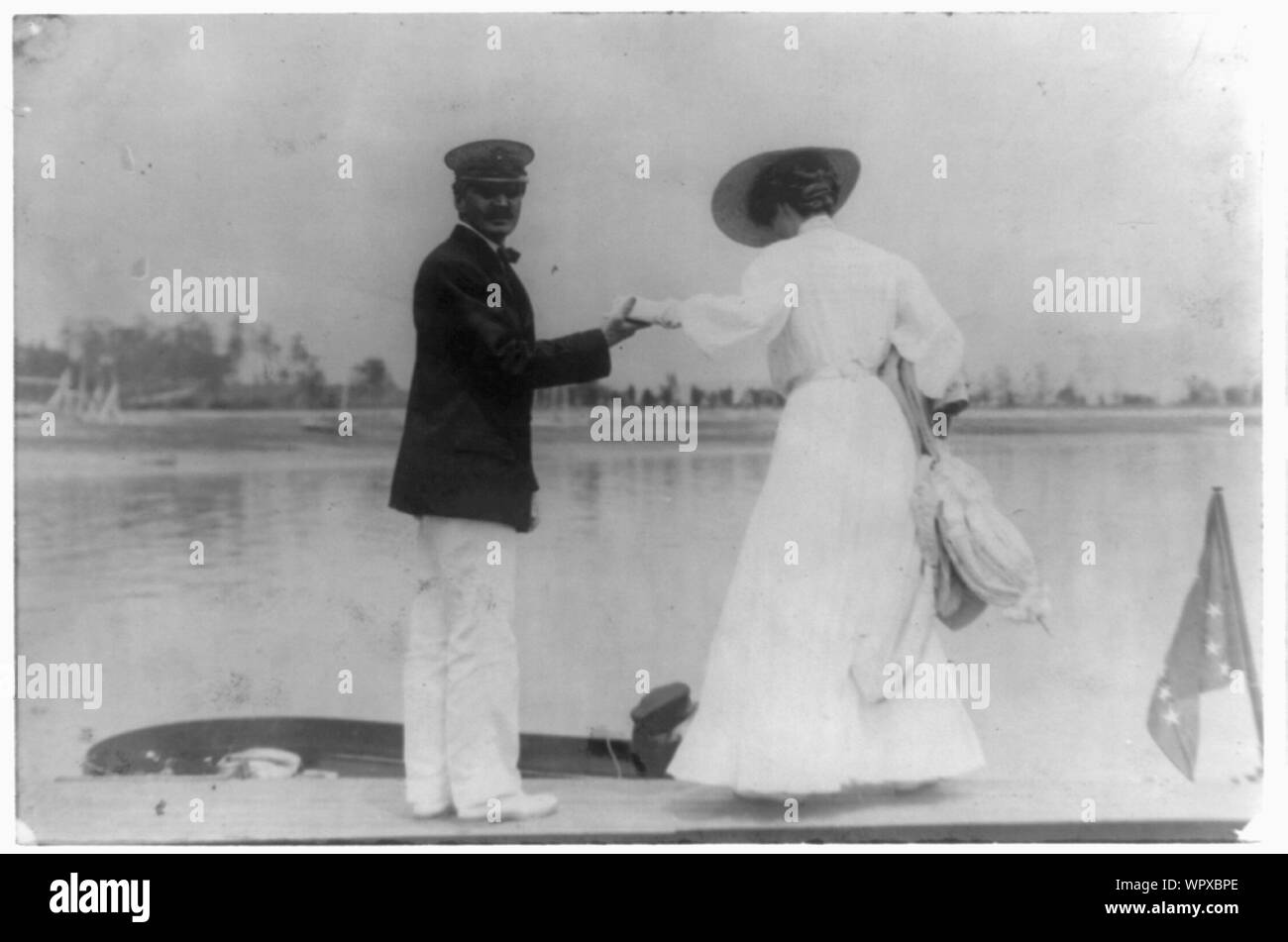 L'uomo ad assistere la donna in barca, Oyster Bay, Long Island, N.Y. Foto Stock