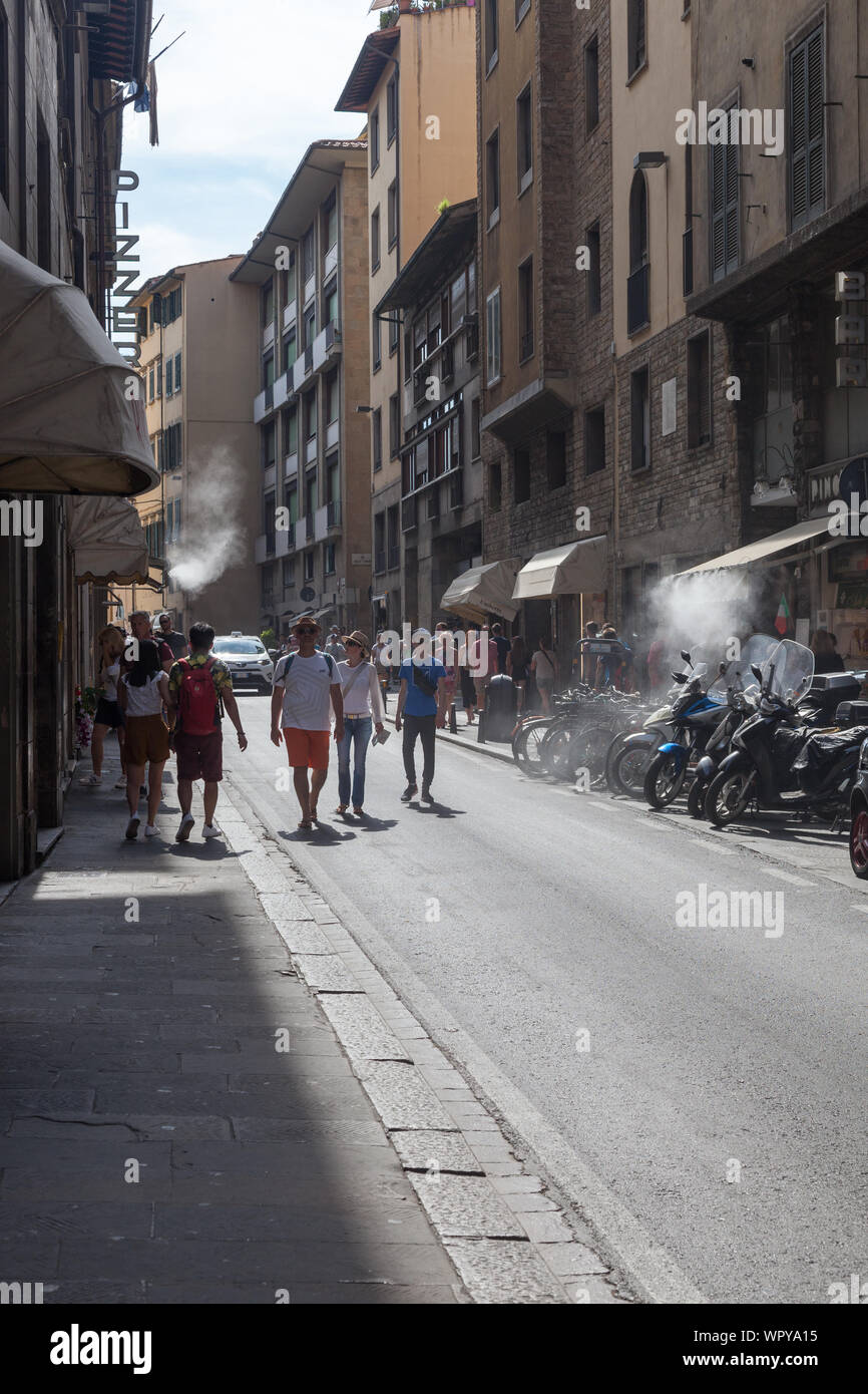 Scena di strada con la nebbia di raffreddamento, i pedoni e i motocicli. Via de Guiccidardini, Firenze, Italia Foto Stock