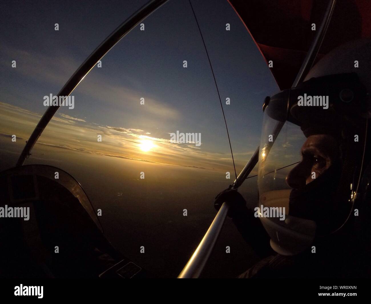 Uomo in deltaplano contro Sky durante il tramonto Foto Stock