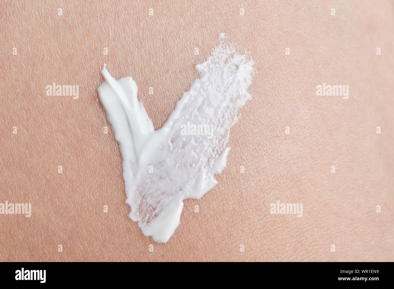 Segno di spunta dal bianco crema per la pelle a pulire il beige colore di sfondo Foto Stock