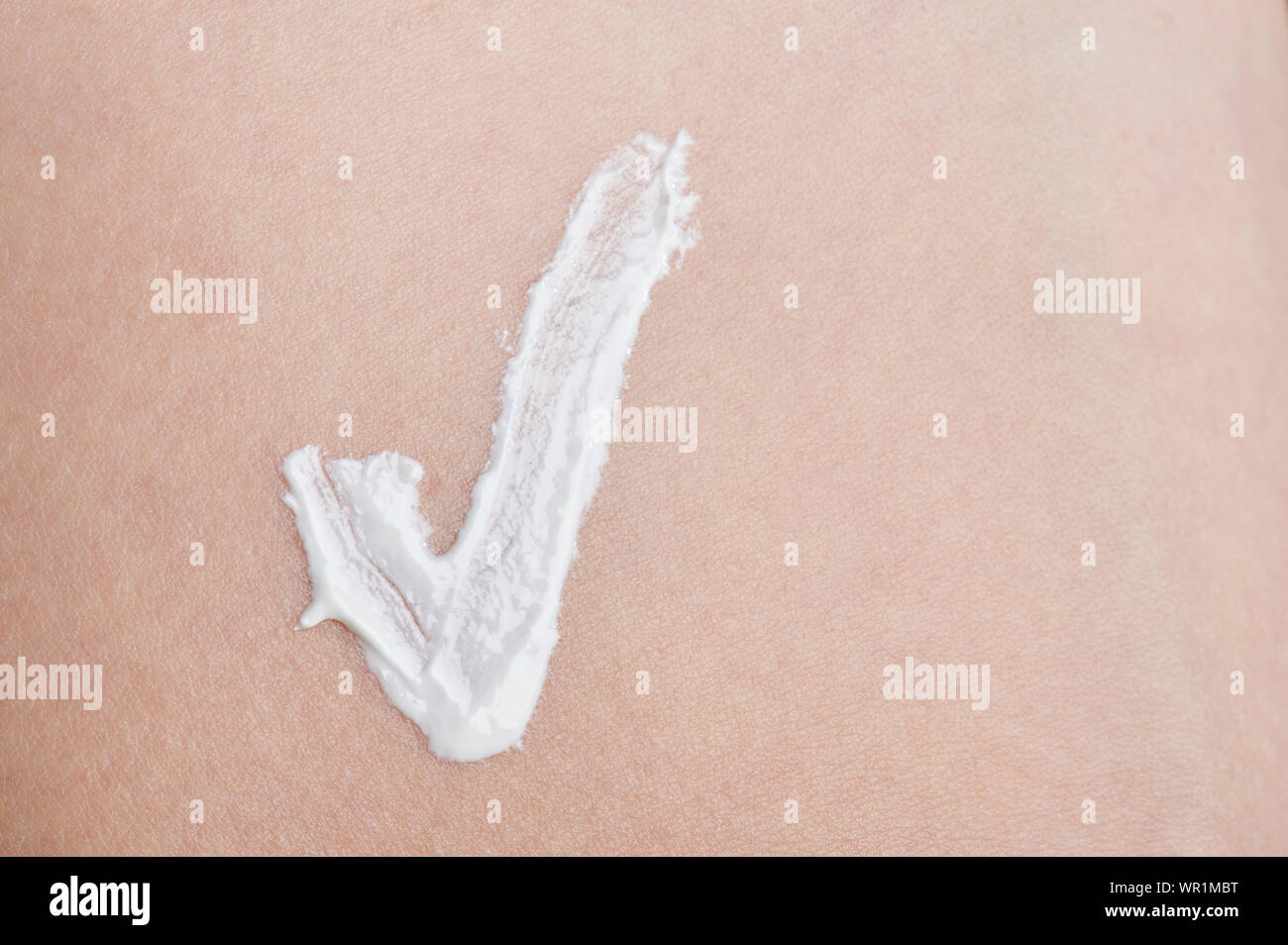 Segno di spunta dal bianco crema per la pelle sulla faccia sfondo Foto Stock