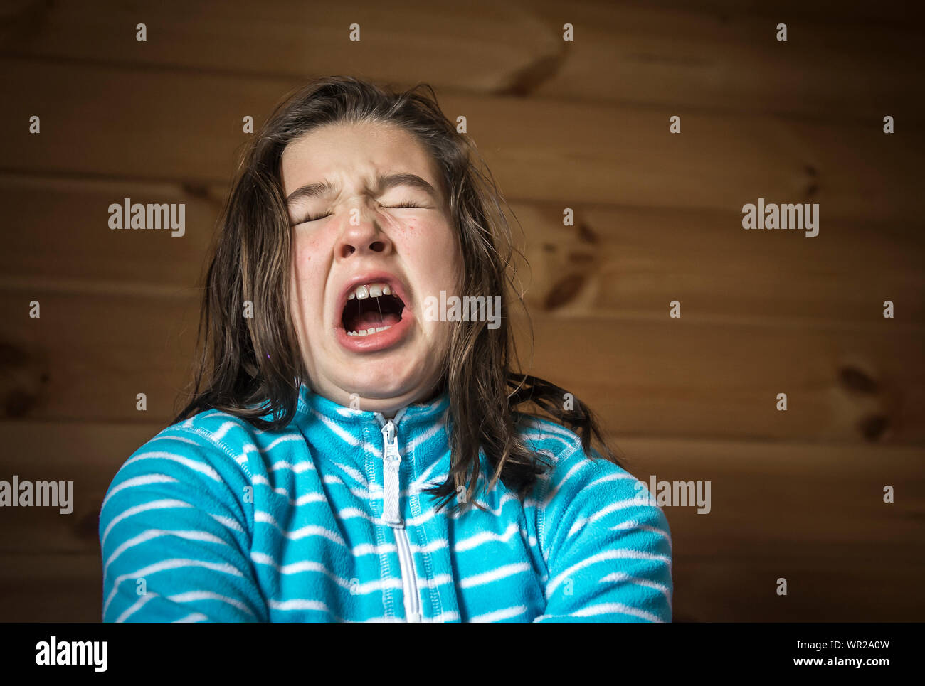 Ragazza arrabbiato grida contro la parete in legno Foto Stock