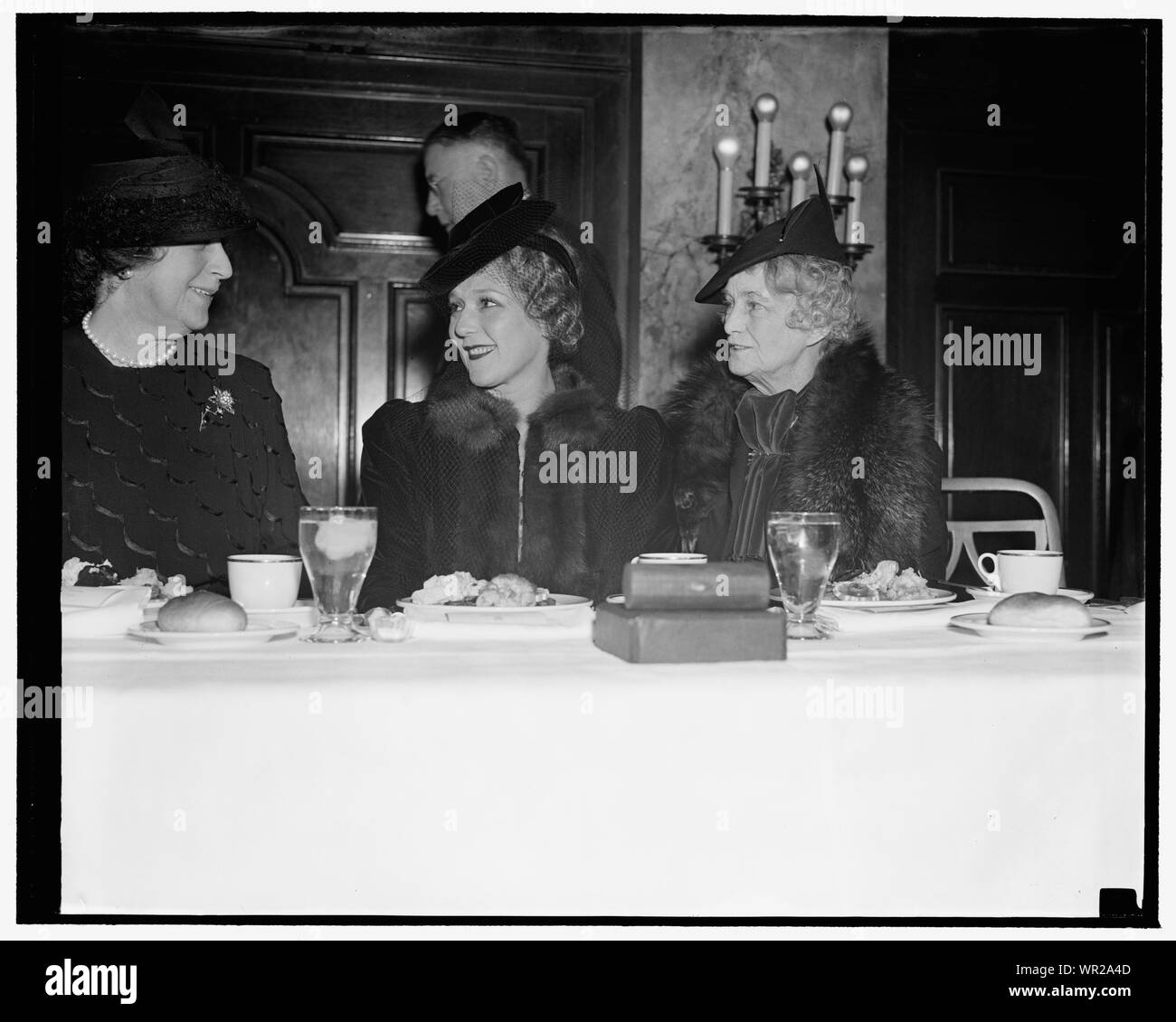 Mary Pickford spezza il pane con cabina mogli in giornale donna pranzo. Washington D.C., nov. 15. La sig.ra Cordell Hull e la Sig.ra Claude A. Swanson, destra, moglie del Segretario della Marina, a impegnarsi in un po' di r[...] con Mary Pickford come essi sono stati ospiti d'onore [...] l'ex star del cinema, alle donne della Nazionale [...] Club pranzo di oggi Foto Stock