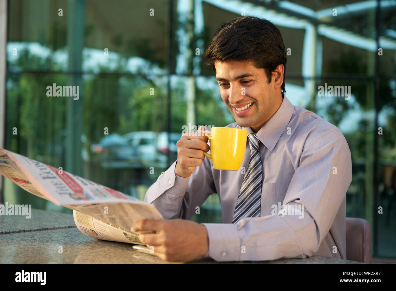 Imprenditore leggendo un giornale e una tazza di caffè Foto Stock