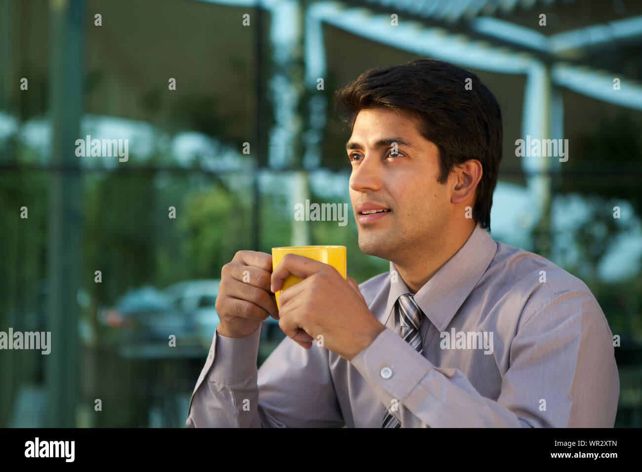 Imprenditore avente una tazza di caffè e sorridente Foto Stock