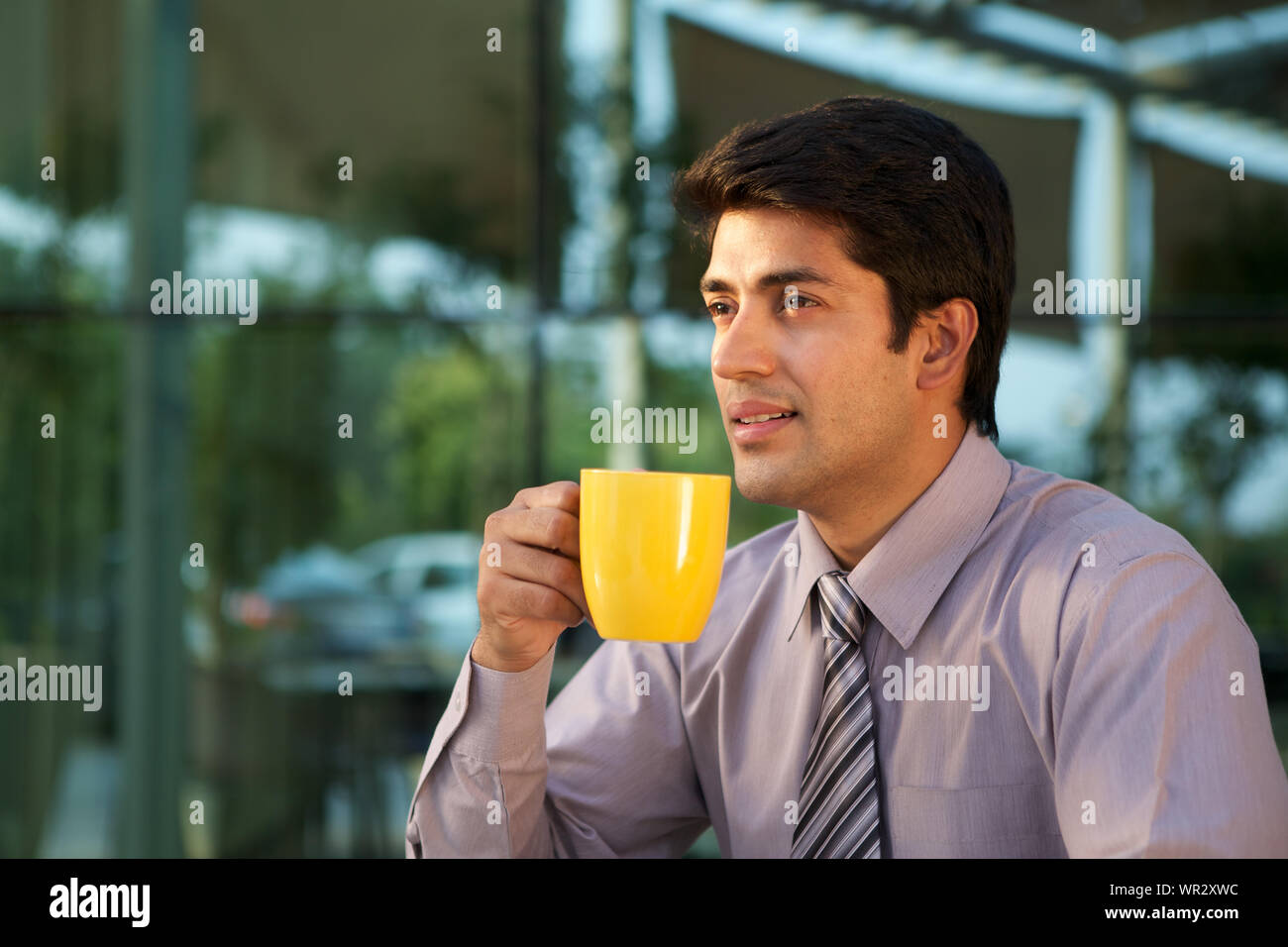 Imprenditore avente una tazza di caffè e sorridente Foto Stock