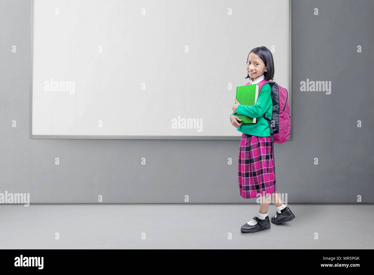 Asian Italian con uno zaino che tiene il libro in piedi con sfondo whiteboard Foto Stock