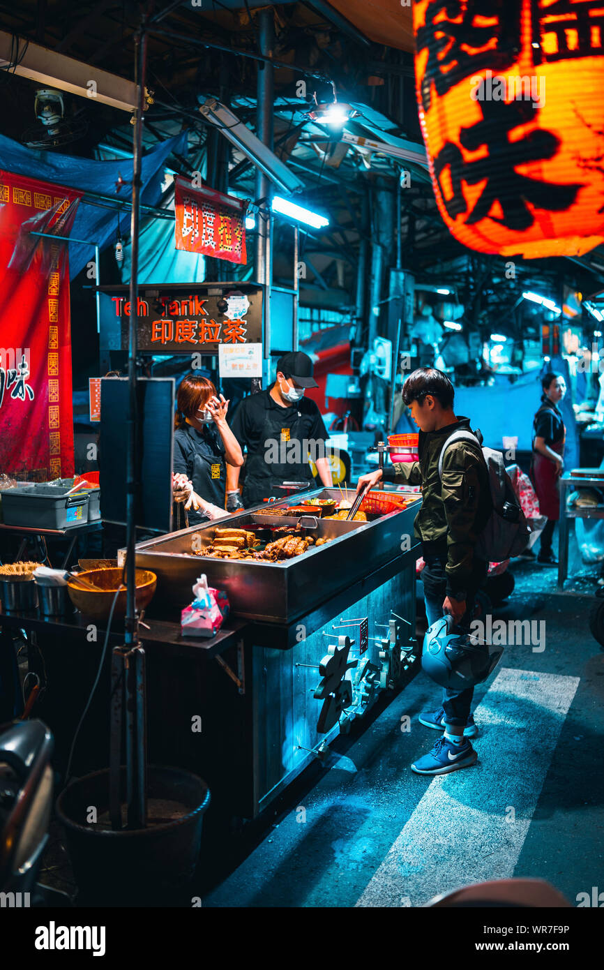 Taichung, Taiwan: il ragazzo è un acquisto di un night snack in un cibo di strada in stallo il mercato notturno in Taichung. Foto Stock