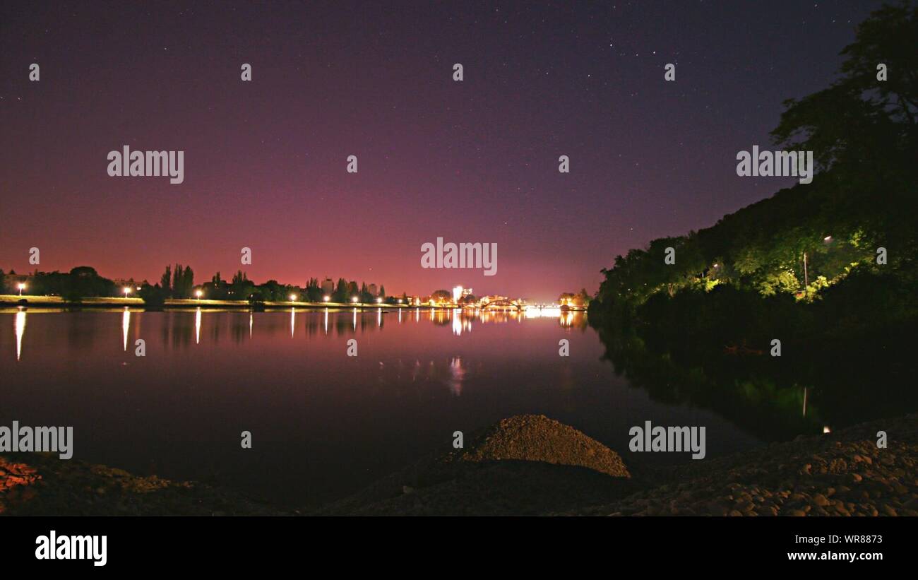 Fiume Vah dalla città illuminata contro il cielo chiaro di notte Foto Stock
